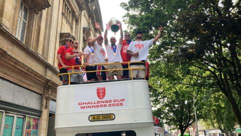 Seven Hull KR players stand on top of an open-top bus one of them is holding the Challenge Cup trophy 