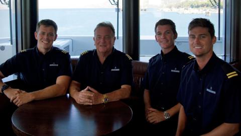 Captain Richard Gascoyne Kirby, Coxswain Ben Owen Bramwell, Trystan Tanner and Bosun Ashley Oliver West sitting around a table and smiling at the camera