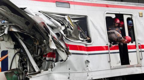 Rescuers looking out from the wreckage of a train collision in Indonesia