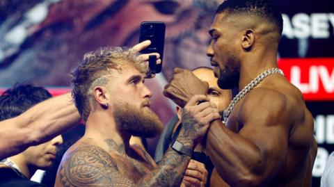 Jake Paul grabs Anthony Joshua's fist during a face-off