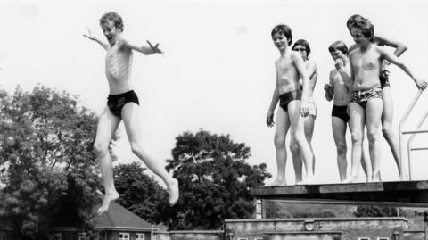 Boys jumping off diving board