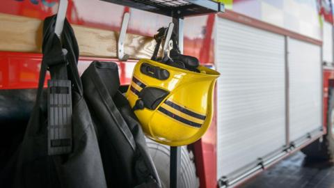 A Fireman's yellow helmet hanging by fire engine in a fire station.