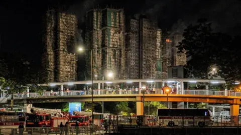 Passers-by view the torched flats