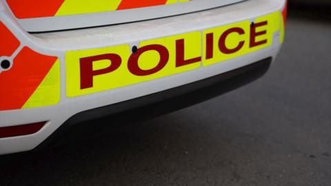Lettering on a white police car reading police in capital letters.
