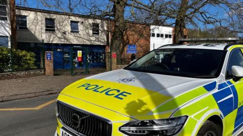 A police car is parked outside a school building