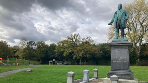 A view of Verdin Park. On the right is the statue of Robert Verdin and on the left can be seen a section of children's playground and a half pipe.