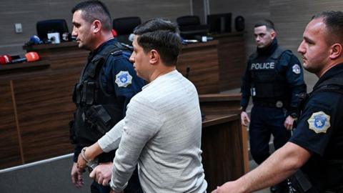 Dušan Maksimović (centre) is seen handcuffed in a courtroom in Pristina after being sentenced to 30 years in prison. Photo: 24 April 2026