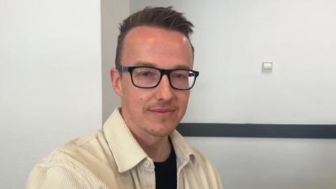 Man in glasses with brown hair looking at camera