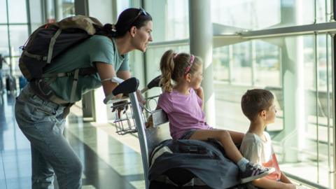 A young family look out of an airport window.