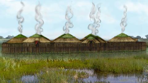 An artist impression of a Bronze Age settlement which is close to water and has several wooden huts surrounded by a high fence made of wooden posts.