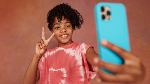a girl holds a mobile phone and takes a selfie