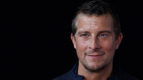 Bear Grylls smiling in front of black background