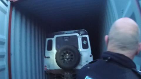 A Land Rover Defender in a shipping container