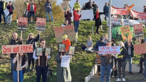 Protestors holding up various signs against the planned new town in Adlington