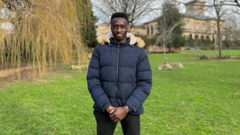 A man standing in park in a puffer jacket