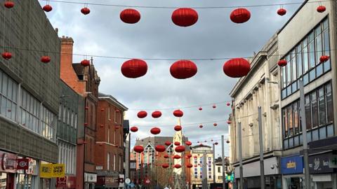 Red Chinese lanterns hanging from building to building in Leicester city centre near the Clock Tower