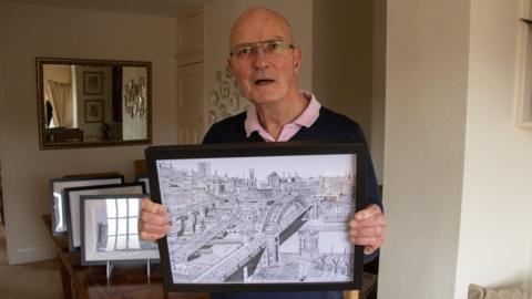 Bill Law, 76, holds up a pen and ink drawing of Newcastle's bridges