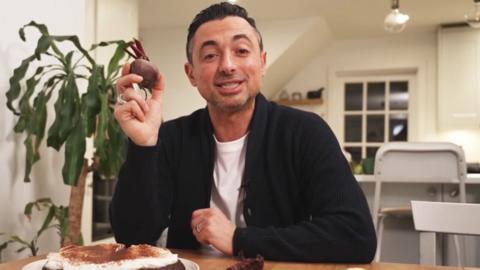 Theo Michaels smiles and holds up a beetroot.
