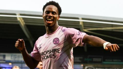 Shrewsbury Town striker Trey Ogunsuyi, wearing the club's pink change strip, celebrates at the final whistle against Chesterfield