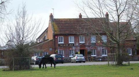 A pony grazes in front of The Alice Lisle, a two-storey brick pub.