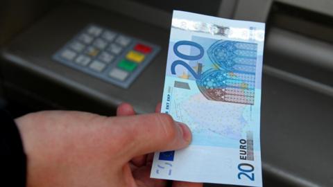 Customer withdrawing 20 euros from cash machine