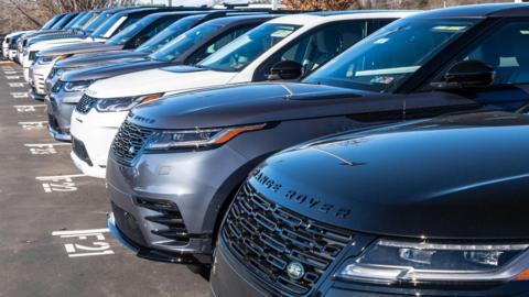 A line of Range Rover cars in a dealership car park