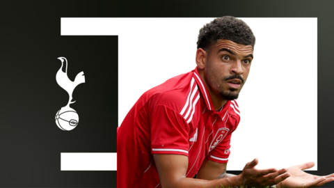 Morgan Gibbs-White holds his palms out in front of a white background and a Tottenham crest