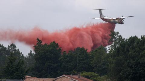 A plane drops fire retardant as efforts to battle wildfires in France.