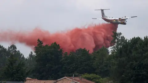 A plane drops fire retardant as efforts to battle wildfires in France.