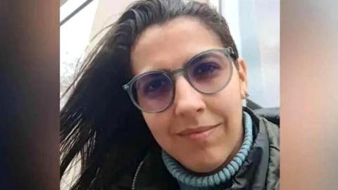 A picture shows the face of Barreto. She is wearing a blue turtleneck under a coat and glasses.