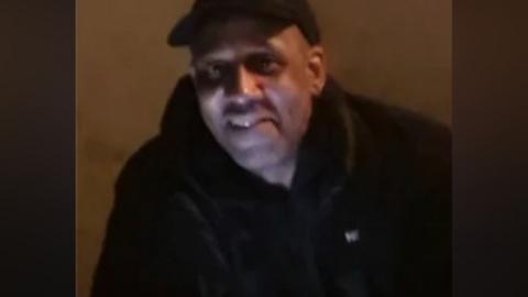 A photo of Anthony - he is wearing a black top and a black cap