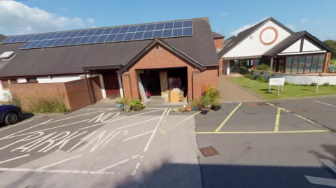 The entrance to Eden Valley hospice is on one site with a one storey brick building to the left with a low row of solar panels on it 