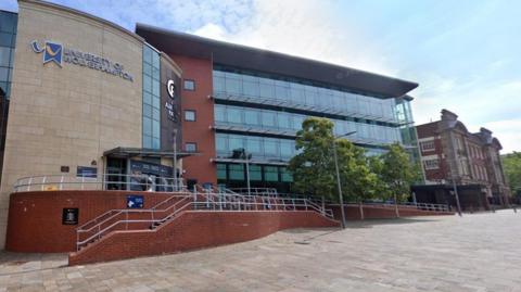 A university building made up of a mix of light yellow and red brick, with a glass facade. On the left side of the building is a sign that says University of Wolverhampton