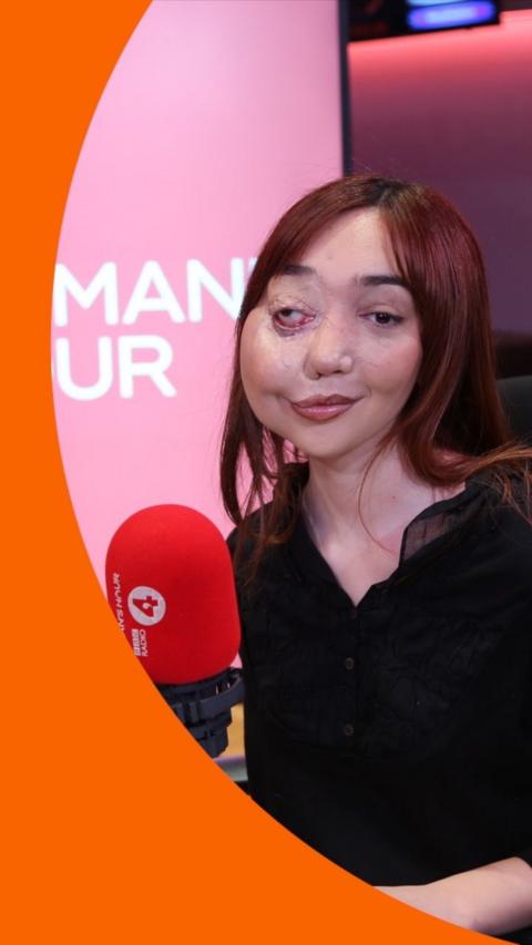 A woman, Nikki Lilly, wears a black top and sits in the Woman's Hour radio studio