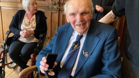 John Avery smiling to camera with this Home Defence medal