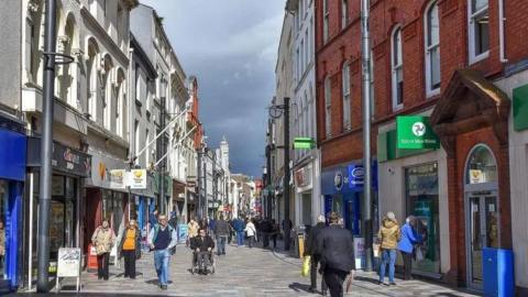 A picture of Strand Street, there are people walking down the street.