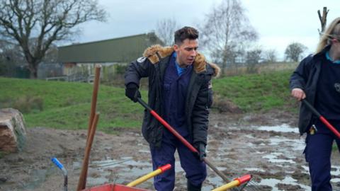 Russell Kane shovelling poo in a zoo