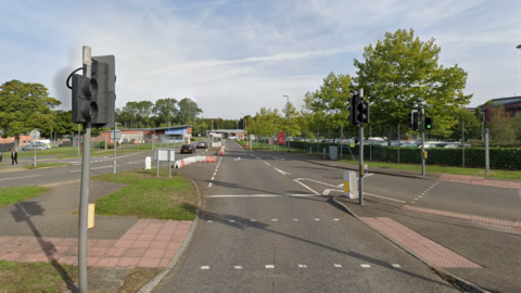 A number of roads are leading to St Omer Barracks. There are traffic lights in the foreground and barriers leading to the barracks in the background.