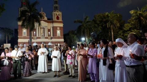 People hold candles as they attend a vigil for the victims of an Air India plane crash