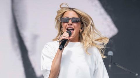 Ellie Goulding wearing a white t-shirt and sunglasses, performing at Radio 1's Big Weekend