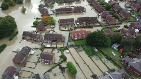 An aerial view of homes surrounded by flood waters