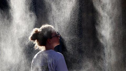 A woman cools off under a mist sprayer in Bordeaux, France.