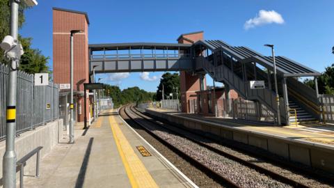 Ashley Down train station is pictured - a railway line with a platform next to it painted with a yellow line, with a footbridge above.