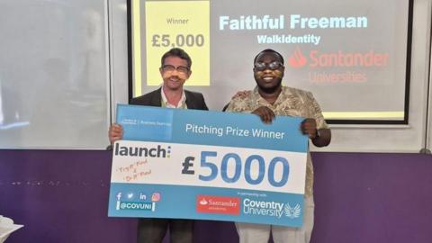 Two men hold a large cheque for £5,000 during a presentation, with a screen behind them showing “Pitching Prize Winner” and “Faithful Freeman.”
