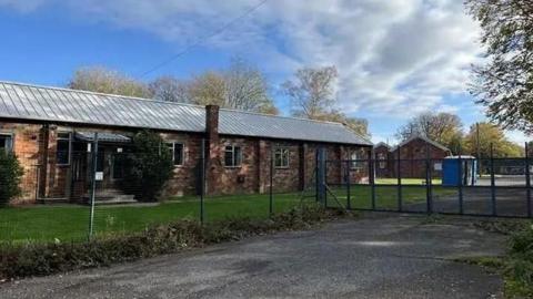An exterior view of Crowborough Training Camp form outside the perimeter fence and locked gates. 
