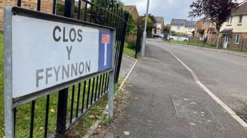 Street sign close up saying Clos y Ffynnon and dead end sign and houses visible behind on quiet street