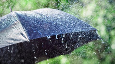 Heavy rain falling on a black umbrella