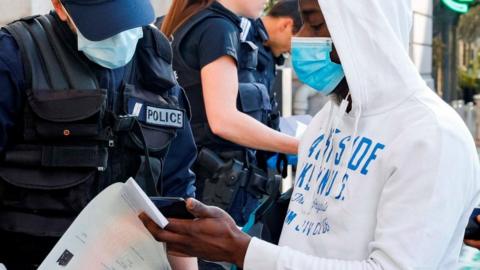 Police officers control people in Paris, 14 April 2020