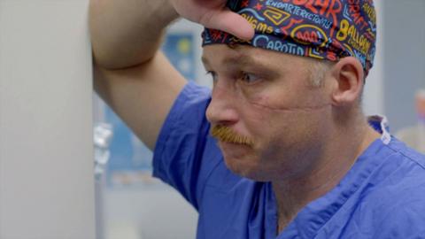 Man wearing blue scrubs and a print bandana.