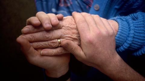 Care worker holding elderly person's hand